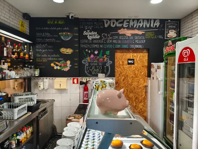 Quadro de giz atrás do balcão com a ementa, a sandes de leitão e a sopa de caldo verde, e um mealheiro em forma de porco