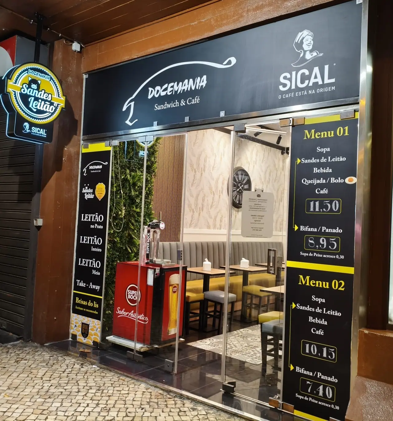 Montra da Docemania no Centro Comercial Maringá à noite, com o letreiro iluminado Sandes Leitão