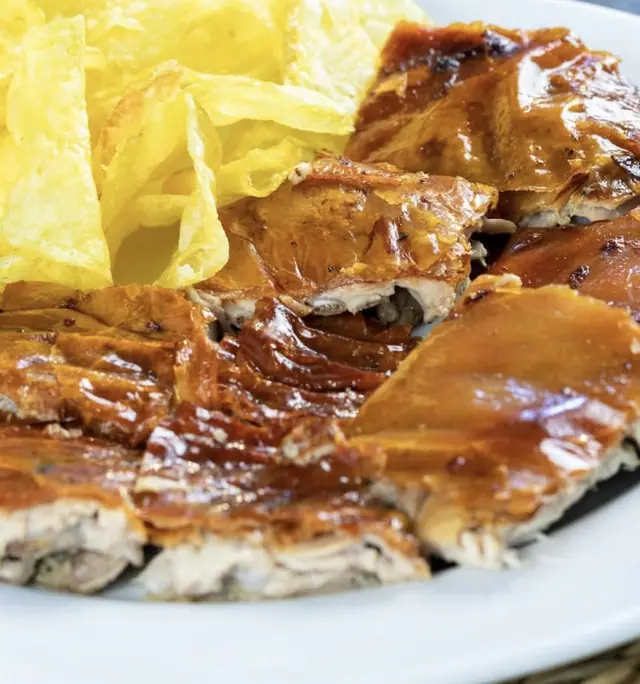 Leitão no prato com a pele dourada e batatas fritas