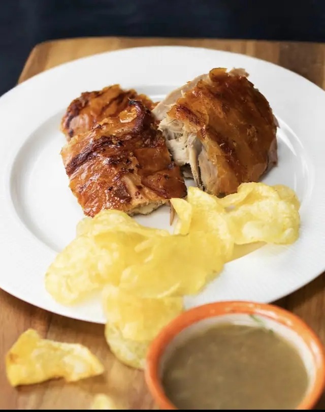 Pedaços de leitão com batatas fritas e uma taça de molho